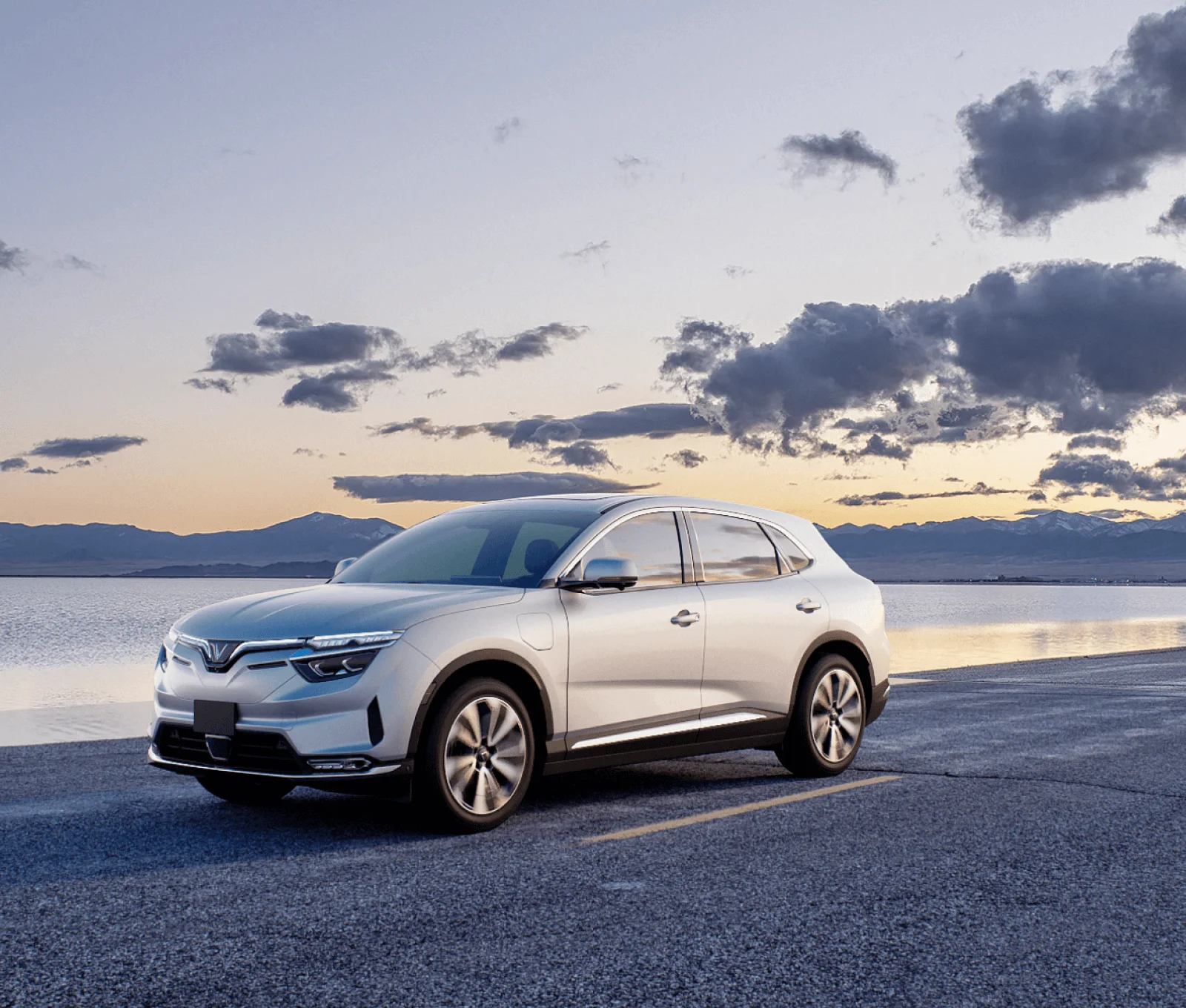 Silver VinFast car parked near the water with a sunset, symbolizing reliability and assurance with VinFast warranty