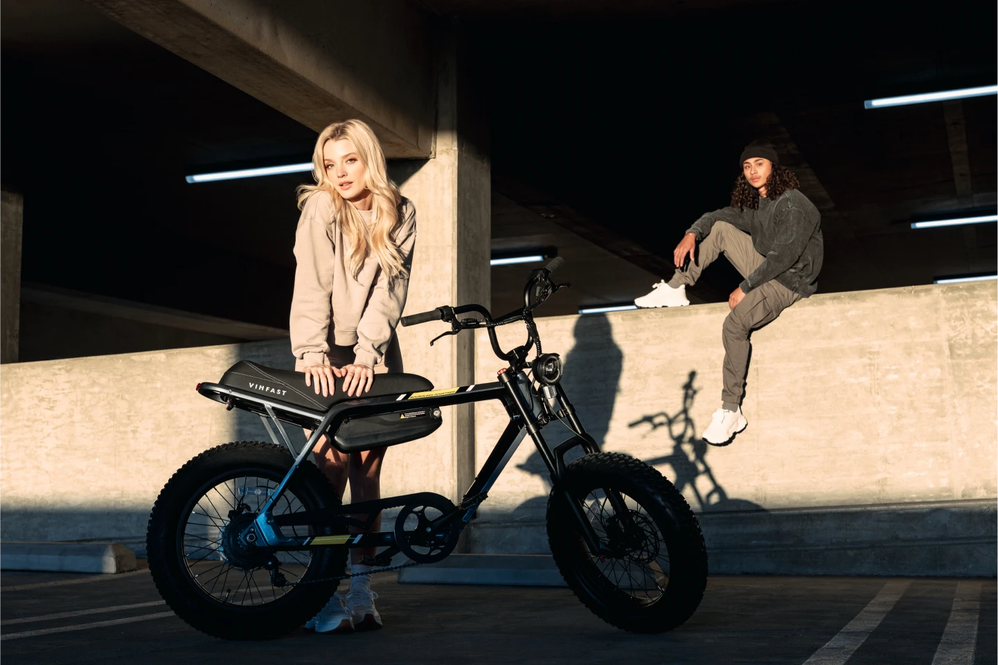 A girl poses with the VinFast electric bike while a guy sits behind her on the ledge