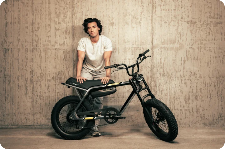 A guy is standing behind his VinFast bike in a parking garage, leaning onto it