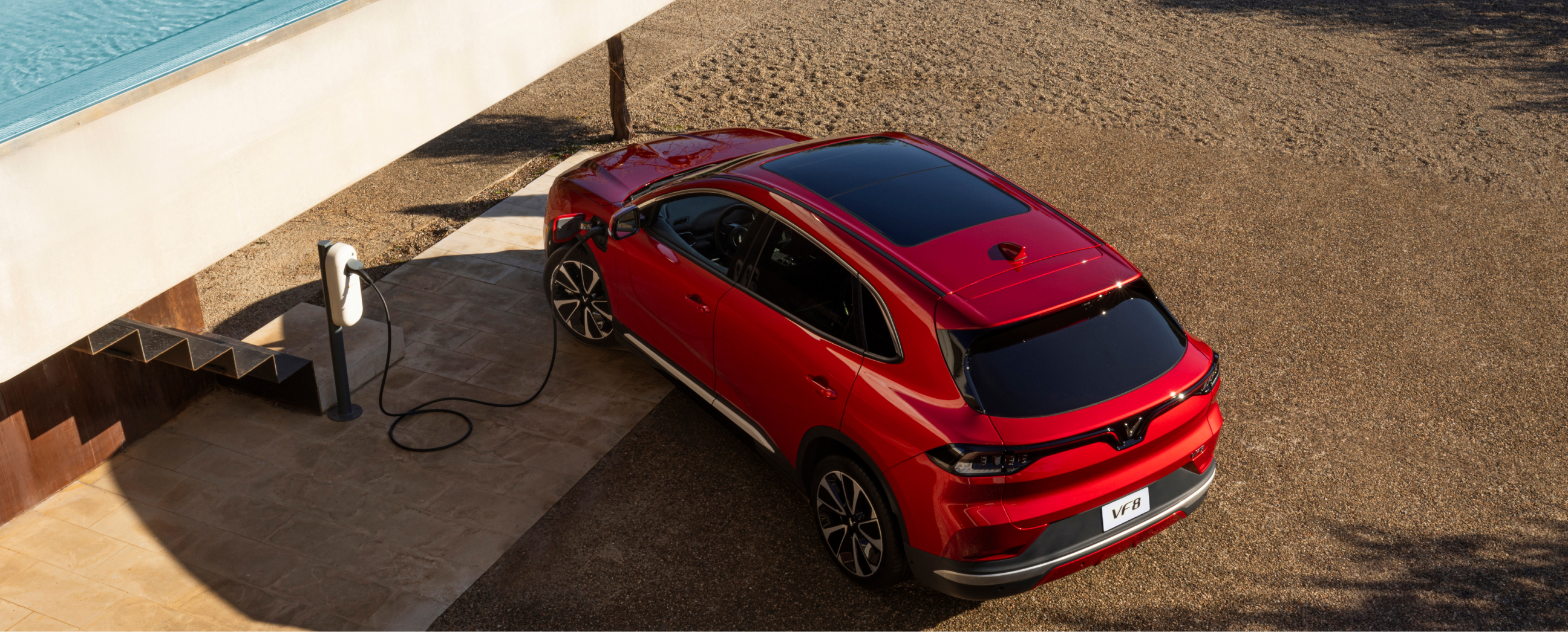 Shiny Crimson Red VinFast VF 8 charging on the sand